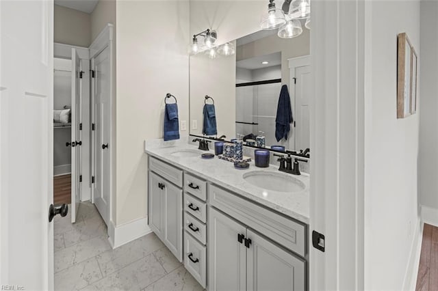 full bath featuring double vanity, baseboards, marble finish floor, and a sink