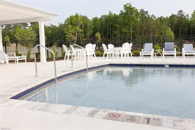 pool featuring a patio, fence, a view of trees, and a pergola