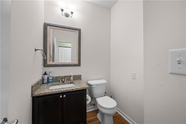 bathroom with vanity, baseboards, toilet, and wood finished floors