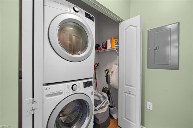 laundry area featuring wood finished floors, laundry area, stacked washer / dryer, and electric panel