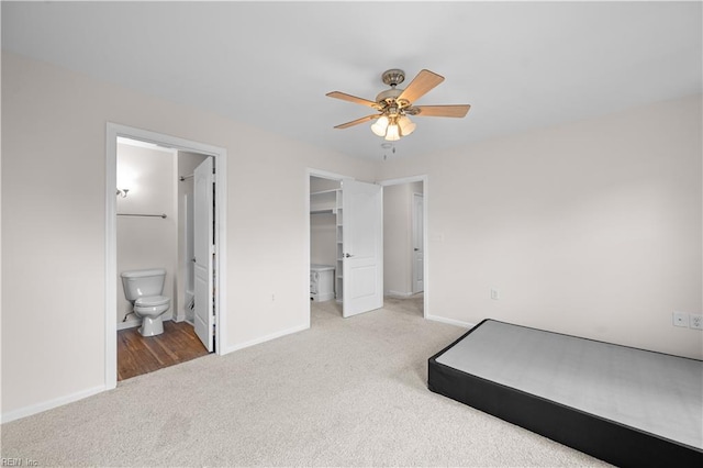 unfurnished bedroom featuring a walk in closet, baseboards, a closet, connected bathroom, and carpet flooring
