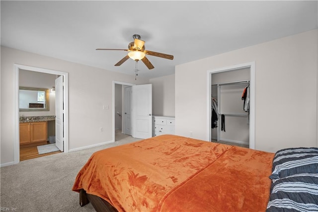 bedroom with a ceiling fan, baseboards, light colored carpet, and ensuite bathroom