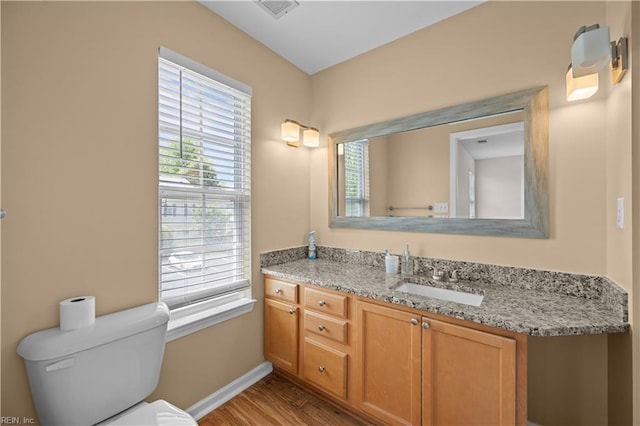 bathroom featuring vanity, toilet, baseboards, wood finished floors, and visible vents
