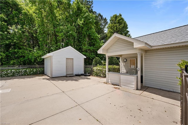 view of patio featuring an outdoor structure, fence, and a shed