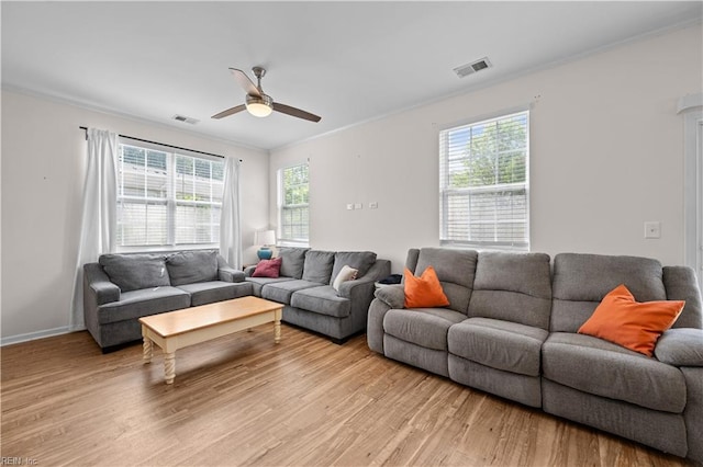 living room featuring visible vents, ornamental molding, and light wood-style floors