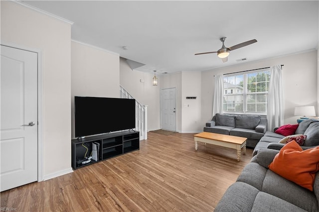 living room featuring a ceiling fan, visible vents, crown molding, wood finished floors, and baseboards