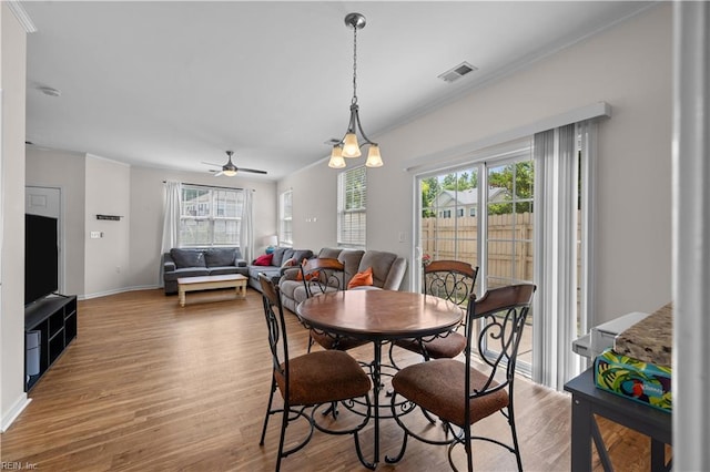 dining room with crown molding, plenty of natural light, wood finished floors, and visible vents
