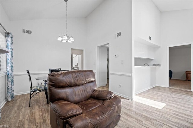sitting room with visible vents, a notable chandelier, and high vaulted ceiling
