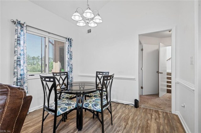 dining area featuring an inviting chandelier, stairway, wood finished floors, and visible vents