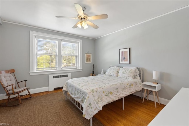 bedroom featuring crown molding, radiator heating unit, wood finished floors, and baseboards