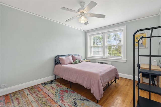 bedroom featuring light wood-style floors, a ceiling fan, ornamental molding, and baseboards