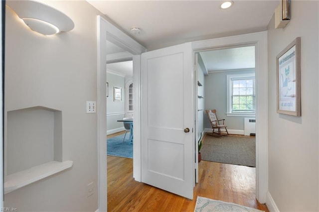 corridor featuring baseboards, recessed lighting, radiator, and wood finished floors
