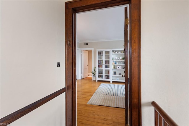 hallway featuring visible vents, ornamental molding, an upstairs landing, and wood finished floors