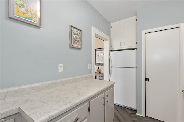 kitchen featuring light countertops, white cabinets, and freestanding refrigerator