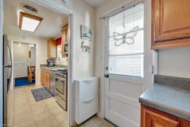 kitchen featuring appliances with stainless steel finishes, a wealth of natural light, a baseboard heating unit, and a sink
