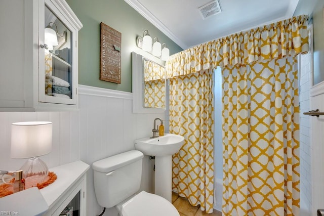 bathroom featuring a shower with curtain, toilet, visible vents, ornamental molding, and wainscoting