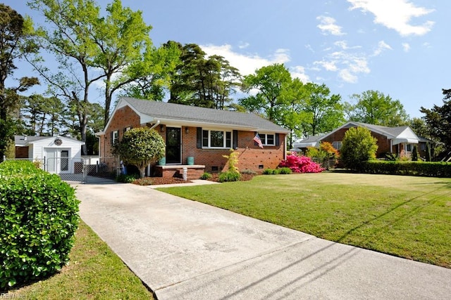 view of front facade with driveway, a gate, an outbuilding, a front yard, and brick siding