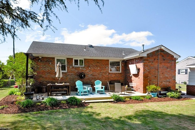 back of property with a deck, a yard, and brick siding
