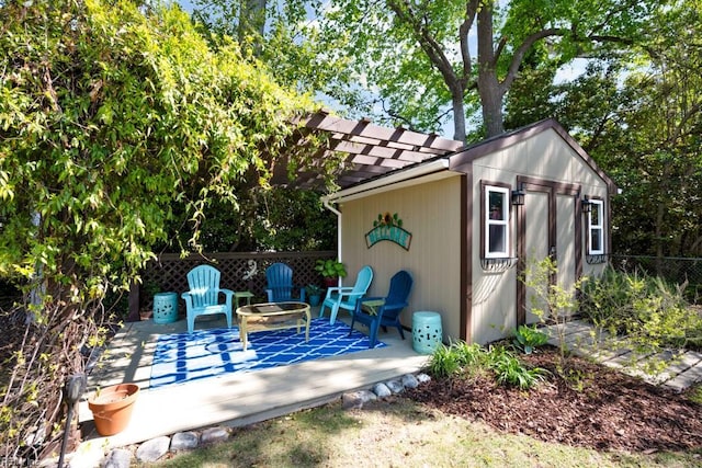 view of outdoor structure with fence, a pergola, and an outbuilding