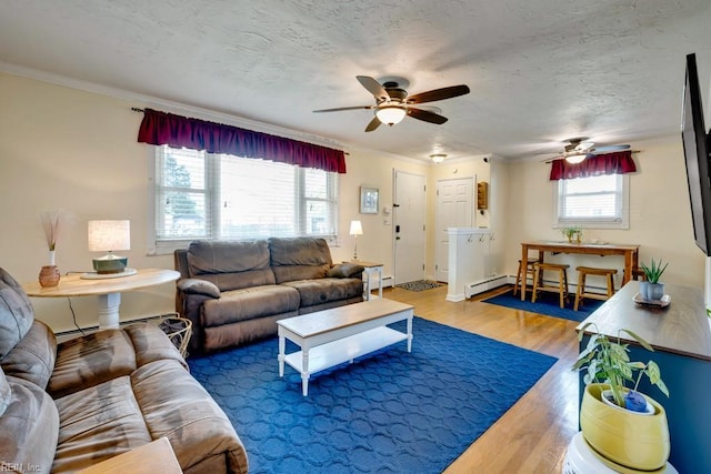 living room with crown molding, a ceiling fan, baseboard heating, and wood finished floors