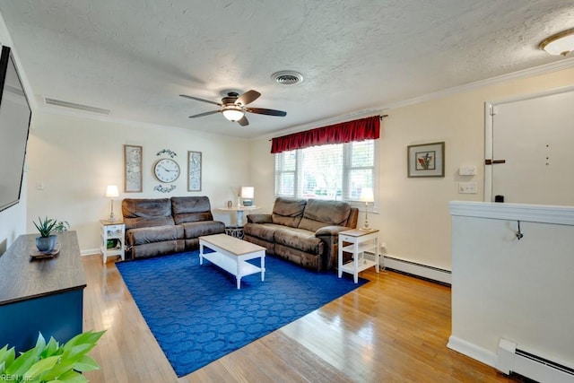 living area with a textured ceiling, visible vents, a ceiling fan, and baseboard heating