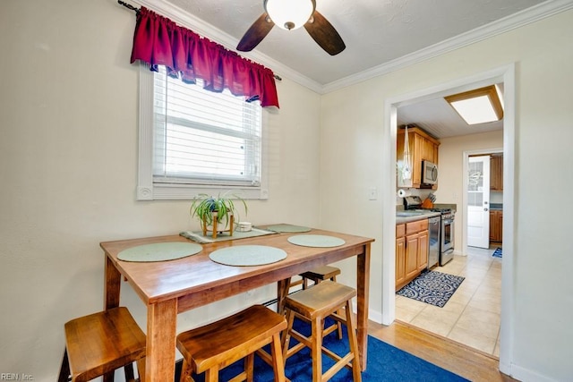 dining space featuring light wood-type flooring, a ceiling fan, a wealth of natural light, and crown molding