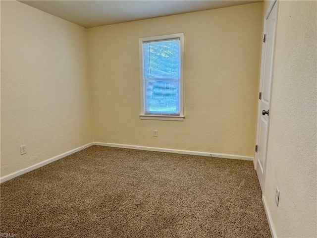 carpeted empty room featuring baseboards and a textured wall