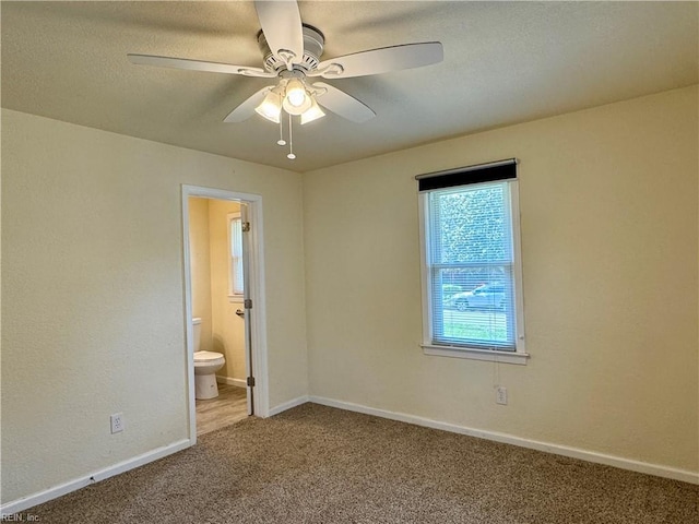 unfurnished bedroom featuring ceiling fan, baseboards, carpet floors, and ensuite bath