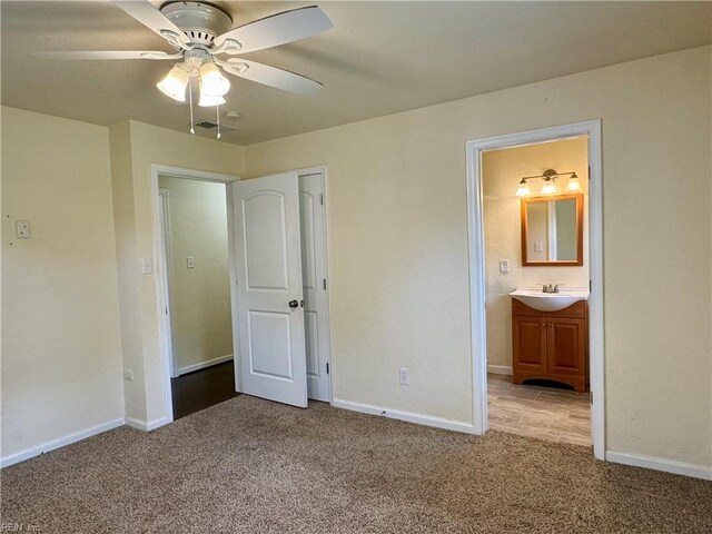 unfurnished bedroom featuring baseboards, light carpet, and a sink