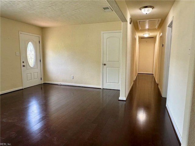 foyer entrance with visible vents, dark wood-style floors, and baseboards