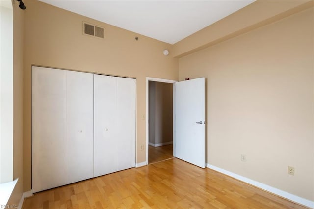 unfurnished bedroom featuring baseboards, visible vents, a closet, and light wood-style flooring