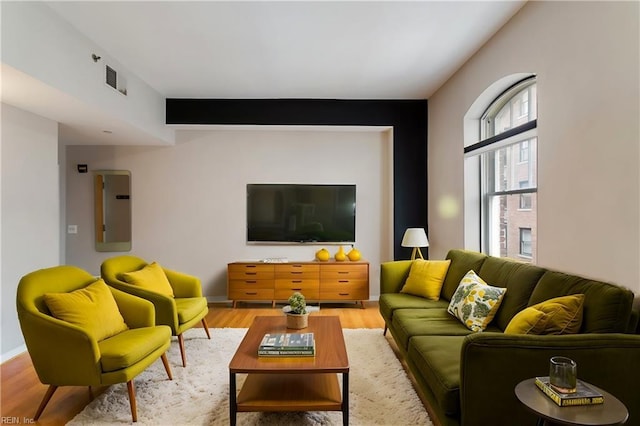 living area with visible vents, wood finished floors, electric panel, and baseboards