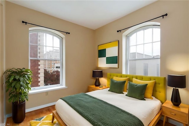 bedroom featuring wood finished floors, baseboards, and multiple windows