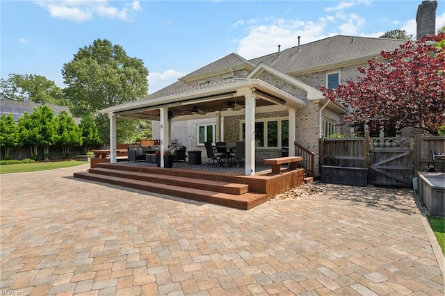 view of patio with a deck, fence, a ceiling fan, and a gate