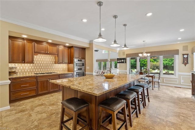 kitchen featuring decorative backsplash, a breakfast bar area, appliances with stainless steel finishes, light stone countertops, and a chandelier