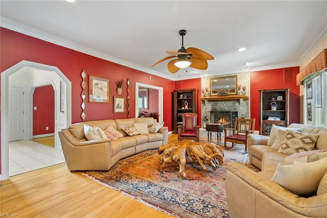 living room featuring crown molding, ceiling fan, a healthy amount of sunlight, and a fireplace