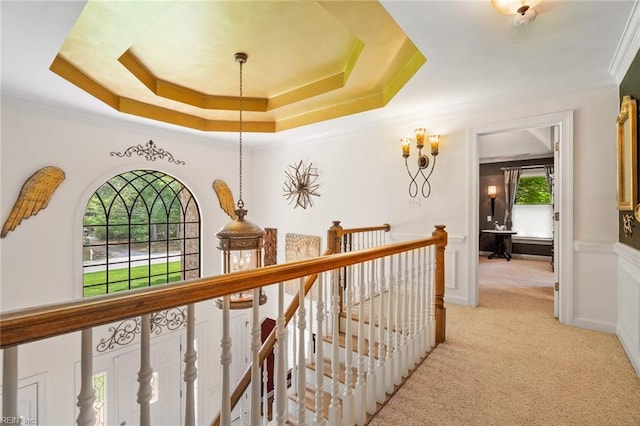 hall featuring crown molding, a tray ceiling, an upstairs landing, and light carpet