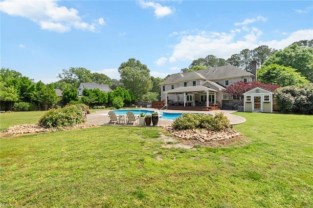outdoor pool with an outdoor structure, a lawn, a shed, and fence