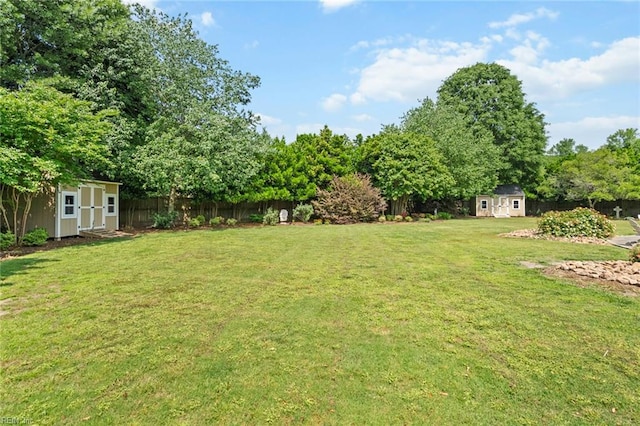 view of yard featuring an outdoor structure, a fenced backyard, and a storage shed