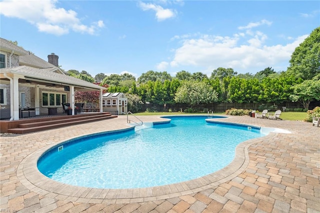 view of swimming pool featuring ceiling fan, fence private yard, a fenced in pool, an outdoor structure, and a patio