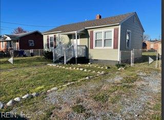 bungalow-style home with a front lawn, a chimney, and fence