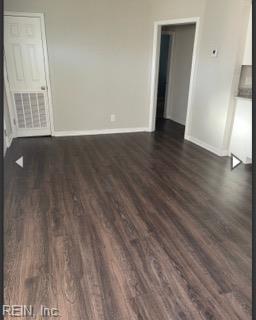 spare room with baseboards and dark wood-style flooring