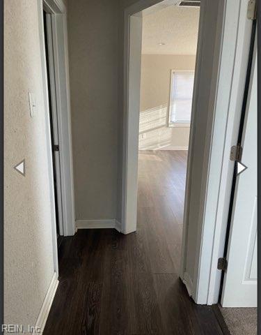 hallway with dark wood-style floors and baseboards