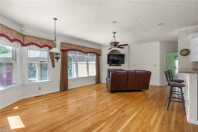 living area featuring light wood-style floors, a ceiling fan, visible vents, and baseboards