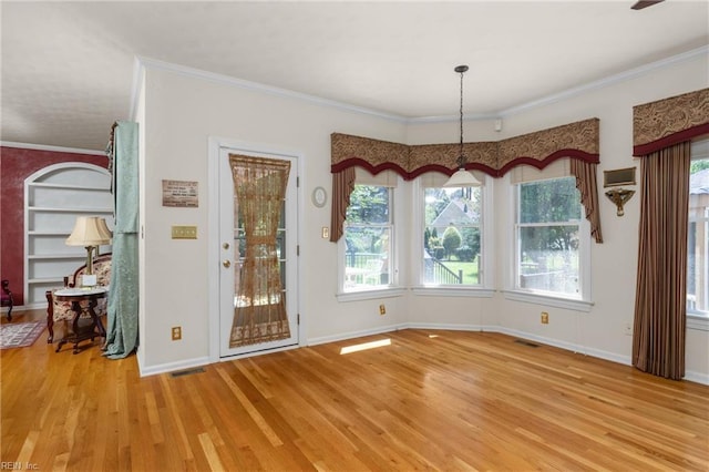 unfurnished dining area with visible vents, light wood-type flooring, ornamental molding, and baseboards