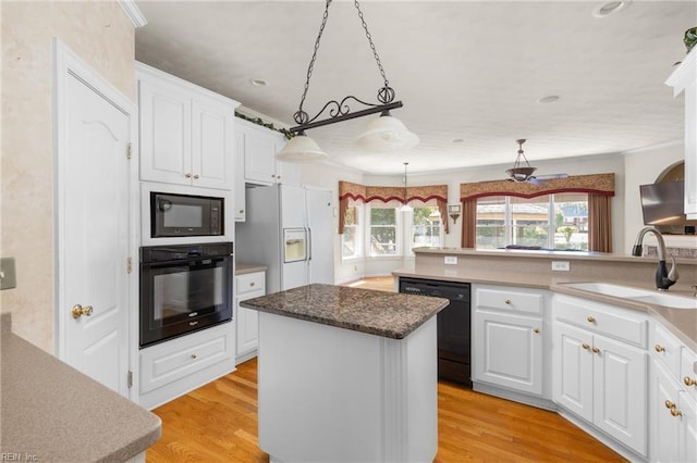 kitchen with a center island, black appliances, a sink, and white cabinetry