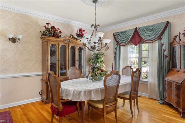 dining room with an inviting chandelier, light wood-style flooring, wallpapered walls, baseboards, and crown molding