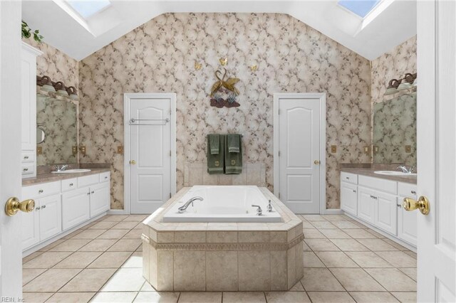 full bathroom featuring tile patterned floors, lofted ceiling with skylight, and two vanities