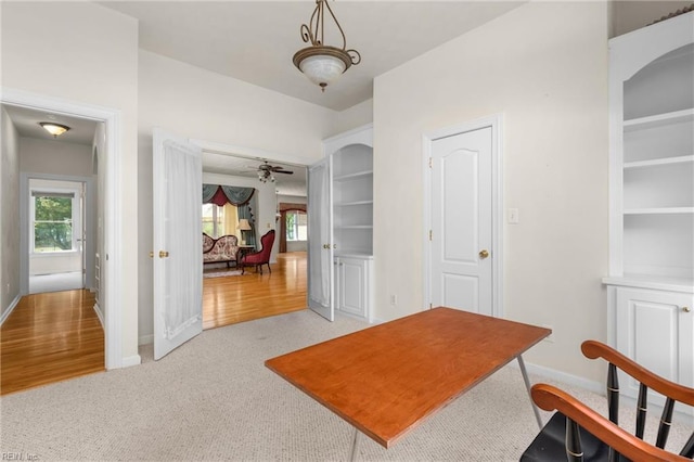 interior space featuring light colored carpet, a ceiling fan, arched walkways, and baseboards
