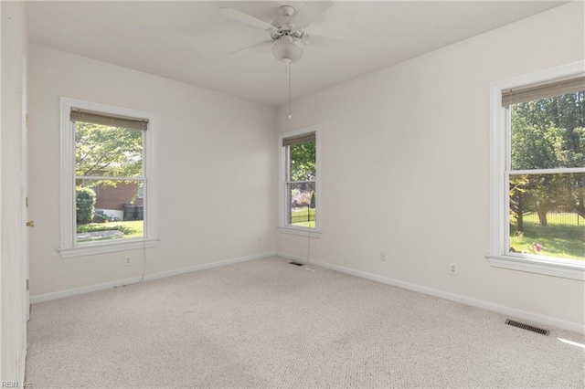carpeted empty room with visible vents, plenty of natural light, and baseboards
